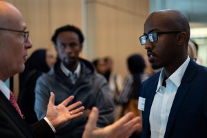 Two students talk with Fuad after his presentation